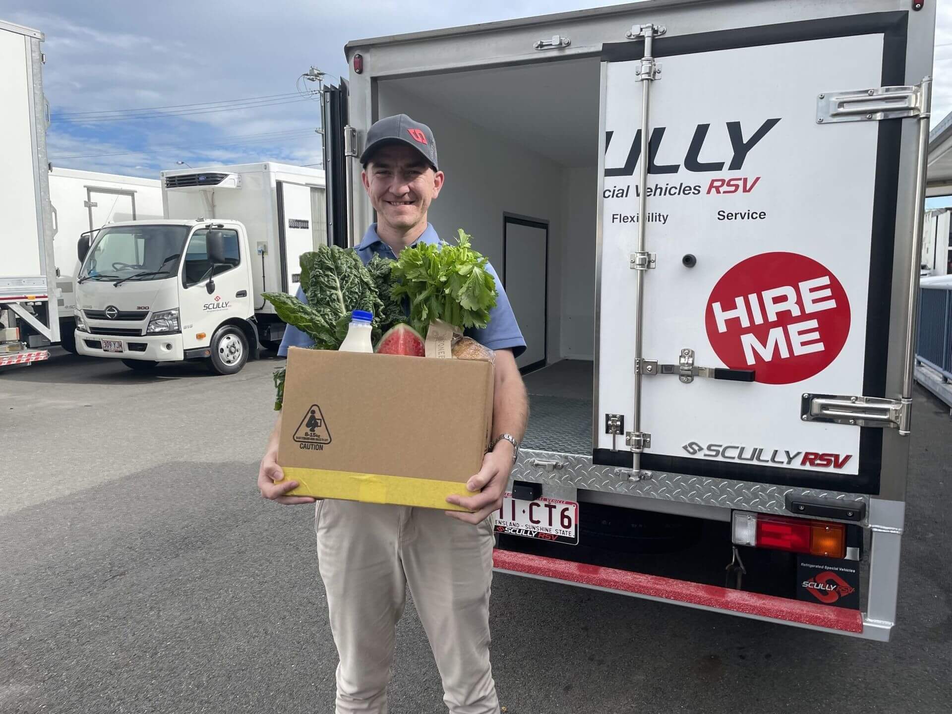 man holding box of food in front of truck