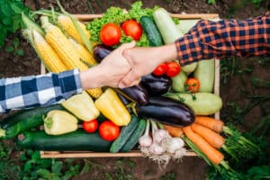 handshake over a crate of vegetables